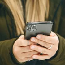 Achtung, SMS! So tricksen Betrüger iPhone-Besitzer aus The girl uses a cell phone with a triple camera.