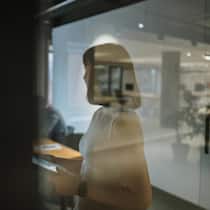 Der Rachefeldzug einer Firma gegen eine Angestellte Photo of a young woman using a tablet in her office, preparing for a meeting, and reviewing meeting notes as she is about to start a professional discussion with her coworkers.