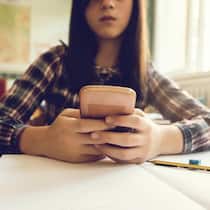 Schluss mit Handy in der Primarschule? Die Mitte fordert ein Verbot Close up of elementary student typing text message on smart phone while sitting at the desk in the classroom.
639440474