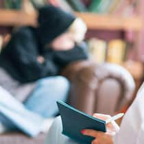 Wer jung zur Therapie geht, wird später von der Kasse bestraft Teenagers gender stereotypes and relationship problems on psychotherapist couch, Blurred student in hoodie sit on couch and listen to female therapist