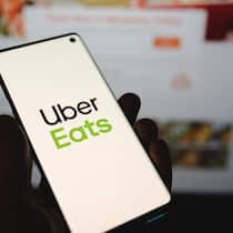 So schnell hat man ein Uber-Abo am Hals Man holding a smartphone with Uber Eats logo in front of the official website. Popular food delivery service on dark blurred backgroundHand with Uber Eats app icon on smartphone