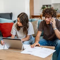 Bank oder Versicherung? Experte warnt vor teuren 3a-Fehlern Young couple sitting on a couch, reviewing domestic budget documents and financial paperwork at home
2242837193