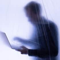 Besonders KMU unterschätzen das Risiko unentdeckter Missstände 2J21B82 Silhoutte eines Büroangestellten steht hinter Plastikfolie mit Laptop