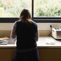 «Die Arbeit einer Mutter zählt heute einfach nichts mehr» Woman standing with her back to the camera, washing dishes in a modern kitchen sink, looking thoughtful
2252619927