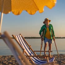 Zuger Prämien-Geschenk wird zur Kostenfalle A senior man with a crutches walking on the beach, enjoying summer vacation. Pensioner recovering after surgery on a trip by the sea. Elderly tourist injured his leg on vacation.
1664984304