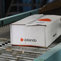 Zweifelhafte Labels bei Zalando und About You Paket von Zalando liegt auf Förderband