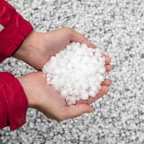 Hagelschäden? In diesen Fällen zahlt die Versicherung Eine Person hat Hagelkörner in der Hand - Unwetter mit Hagel führen oft zu Schäden an Autos, Gebäuden und Möbeln. Welche Versicherung springt ein, wenn etwas beschädigt wurde
