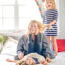 «Ich habe keine Zeit für Achtsamkeit» Wie soll man Achtsamkeit in einen ausgefüllten Alltag einbauen? Eine erschöpfte Mutter sitzt mit ihren Kindern auf dem Bett.