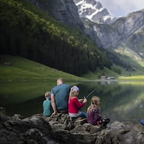 Wandern mit Kindern – dank diesen Tipps haben alle ihren Spass Familie sitzt am See - Damit die Kinder keine schlechte Laune beim Wandern bekommen, sollte man ein paar Punkte beachten