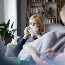 Partner krank – ist Kürzung gerecht? Mutter sitzt krank auf dem Sofa