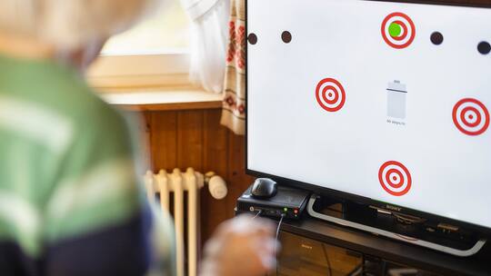 Ein Bildschirm mit Kreisen und einer verschwommenen Frau davor. Exergaming soll gegen Demenz vorbeugen.