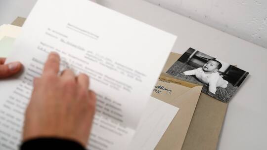 Foto eines Babys in einem Umschlag zusammen mit Dokumenten