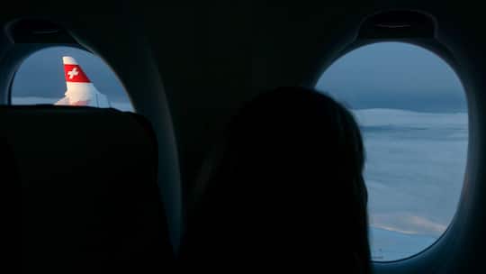 Eine Frau schaut aus dem Fenster einer Swiss-Maschine. Bei der Swiss können auf Kurzstrecken bald gratis bald Whatsapp-Nachrichten verschickt werden.