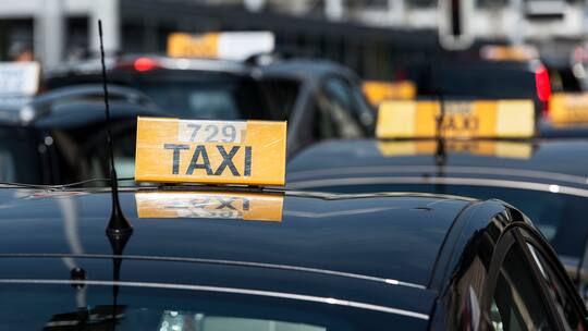 Gelbes Taxi-Schild auf schwarzem Auto am Taxistandplatz am Zürcher Hauptbahnhof