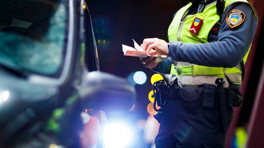 Das Bild zeigt einen Polizisten bei einer Autokontrolle