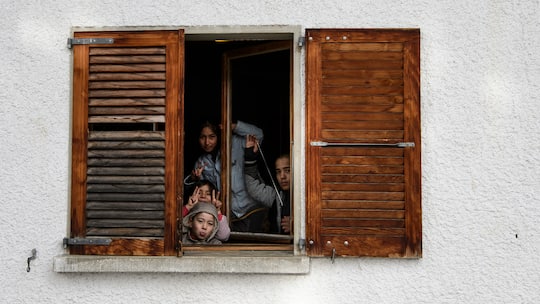 Asylsuchende Kinder posieren hinter einem Fenster in der Asylunterkunft Gryon bei Villars-sur-Ollon. Von 30’000 zusätzlichen Flüchtlinge in der Schweiz ist die Rede in diesem Jahr. Das lässt die Gemeinden Alarm schlagen. Sogar linke Parteien fordern harte Massnahmen.