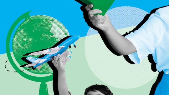 Ein Kind hält ein Spielzeug-Flugzeug vor einem Globus. Wie man mit Minderjährigen stressfrei reist.