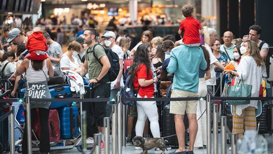 Viele Menschen mit Koffern warten in einer Schlange am Flughafen.