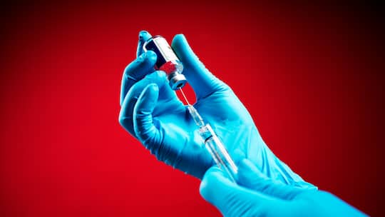 Hand mit Spritze; Soll ich mich gegen Covid impfen lassen? Es kursieren mehrere Covid-Varianten. Bei wem eine Impfung empfohlen wird.