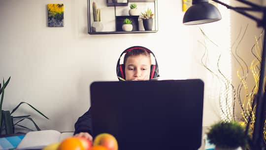 Ein Jugendlicher mit Kopfhörern sitzt vor einem Laptop. Seit dem 1. Januar 2025 muss bei Videospielen und Filmen das Mindestalter angegeben werden, um Jugendliche besser vor ungeeigneten Inhalten zu schützen. Das regelt das neue Jugendschutzgesetz im Detail.