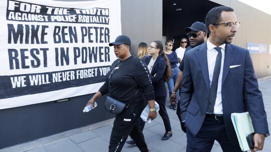 Personen vor dem Strafgericht des Bezirks Lausanne, im Hintergrund Plakat für Mike Ben Peter