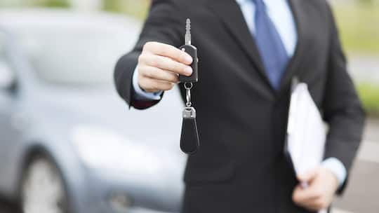 Ein Anbieter von Leasingwagen übergibt einer Kundin den Schlüssel zum Auto.