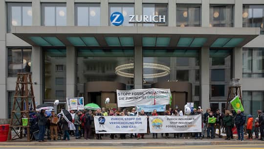 Eine Gruppe von Klima-Aktivistinnen protestiert mit Bannern vor dem Haupteingang der Zurich Versicherung