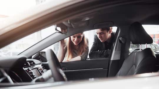Junges Paar schaut in ein Auto - Ein Kunde kauft eine Occasion. Erst nach hartnäckigem Nachfragen erfährt er, dass es ein Mietauto war. Die Garage hat trotzdem nicht gesetzeswidrig gehandelt