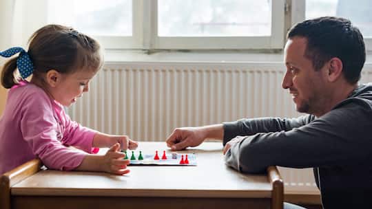 Ein Vater spielt mit seiner kleinen Tochter ein Gesellschaftsspiel. Kleinkinder lernen durch das Spielen wichtige Fähigkeiten für ihre Entwicklung. Eine Einschätzung einer Entwicklungspsychologin.