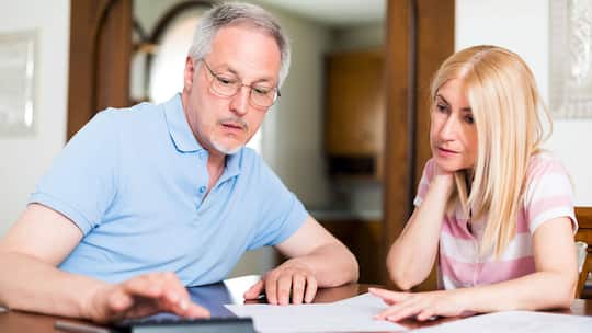 Eine Frau und ein Mann sitzen zusammen am Tisch und studieren Unterlagen.