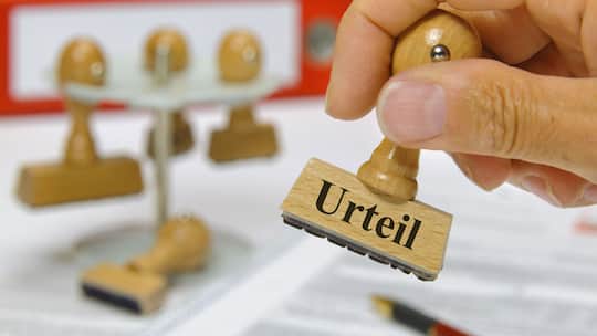 Eine Person hat einen Stempel in der Hand. Auf dem Stempel steht das Wort "Urteil".