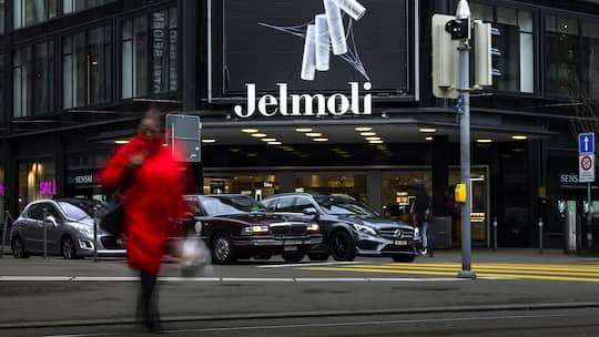 Fassade des Jelmoli-Warenhaus an der Zürcher Bahnhofstrasse, davor eine Passantin, welche die Strasse überquert. Wer im Online-Shop von Jelmoli bestellt, landet unter Umständen auf einer Website, die indirekt mit dem Warenhaus zu tun hat.