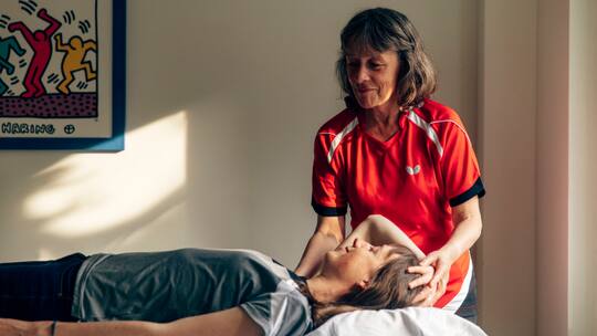 Die blinde Physiotherapeutin Rita Dütsch behandelt eine junge Patientin am Nacken.