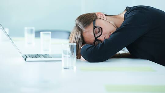 Eine Frau macht im Büro ein Nickerchen.