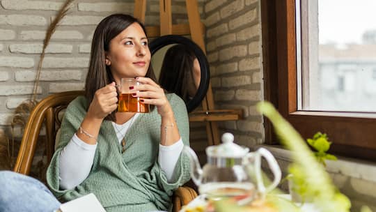 Frau sitzt mit einer Tasse Tee auf dem Sofa