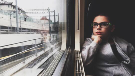 Bub sitzt im Zug und schaut aus dem Fenster