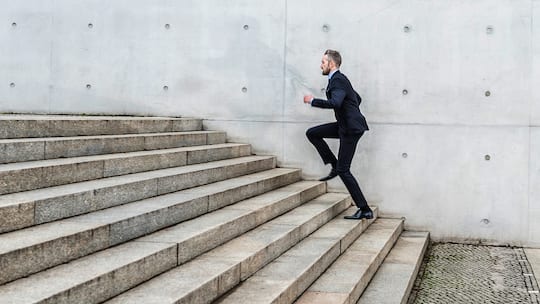 Mann steigt die Treppe hoch - Jahrelang hiess es, wir sollten 10’000 Schritte pro Tag gehen, um gesund zu bleiben. Aktuelle Studien zeigen, dass es gar nicht so viel braucht. Aber: Es gibt einen Fehler, den Sie vermeiden sollten