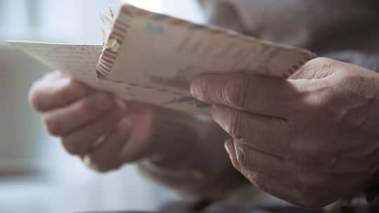 Älterer Mann hält Couvert in der Hand