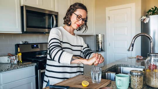 Frau presst Zitrone in Glas mit Wasser