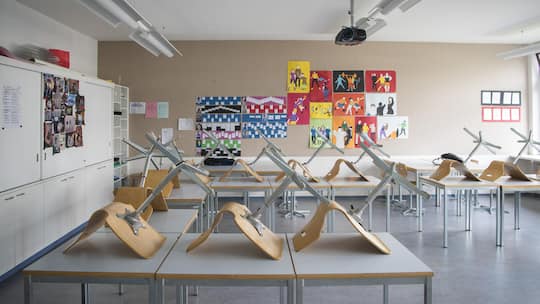 Stühle auf Pulten im Klassenzimmer - Während im Büro klare Temperaturregeln gelten, schwitzen Schulkinder bei bis zu 35 Grad im Unterricht. Der Lehrerverband fordert nun einen Hitzeplan für Klassenzimmer