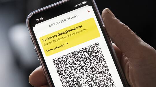 Person hält Handy mit der Meldung der verkürzten Gültigkeitsdauer des Covid-Zertifikats