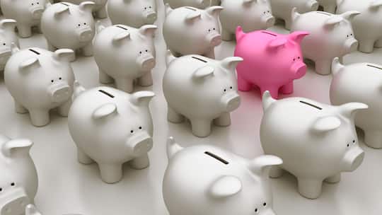 Pinkes Sparschwein inmitten vieler grauen Sparschweine