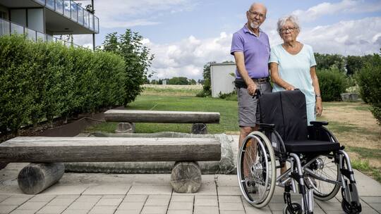 Reinhard und Ursula Saller vor ihrem Grundstück mit dem Rollstuhl