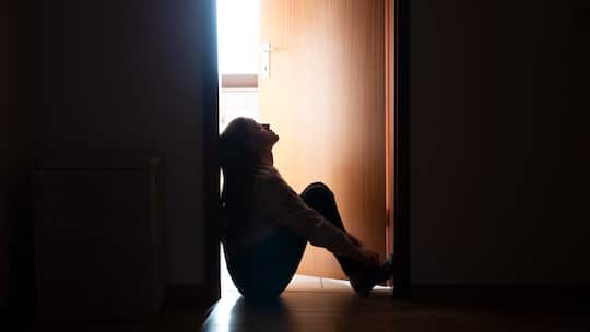 Trauriges Teenager-Mädchen sitzt auf dem Boden vor der Zimmertür