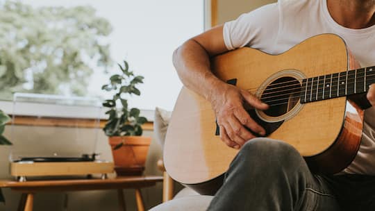 Mann spielt zuhause Gitarre