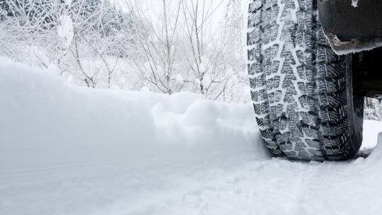 Ein Auto fährt auf einer verschneiten Strasse mit Winterpneus - Es wird wieder Zeit für Winterreifen. Was man dabei beachten muss