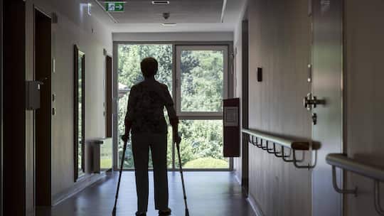 Ältere Frau geht im Spital an Krücken