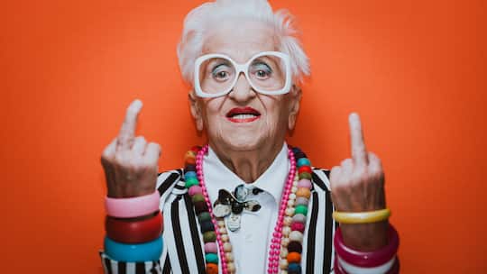 Doppelter Stinkefinger von älterer Dame mit coolem Schmuck.