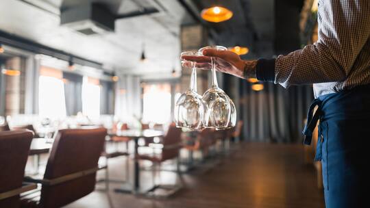 Servicekraft in Restaurant trägt Gläser