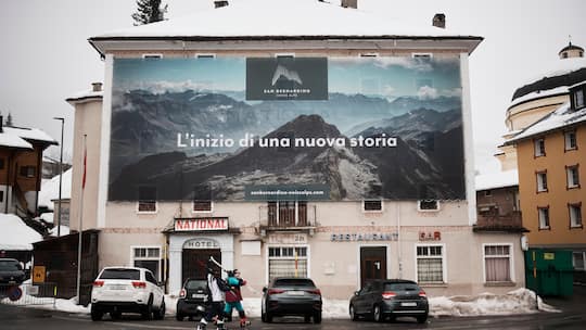 Das «Hotel National» in San Bernardino, zwei Frauen mit Skiern auf den Schultern gehen vorüber.